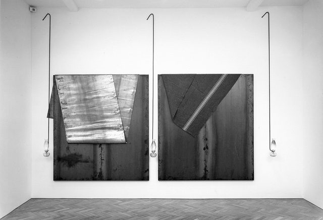 ST_1990_due_lastre_doppie_con_foglio_di_piombo_e_coperta_appoggiati_in_cima_e_tre_lampade_a_olio_appese_a_tondini