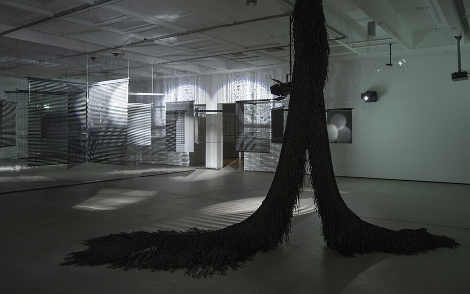 Heague Yang, Installation view: Triple Vita Nestings, Institute of Modern Art, Brisbane. In view (l-r): Lethal Love, 2008/2018, Aluminum venetian blinds, powder-coated aluminum hanging structure, steel wire rope, free-standing mirror wall, moving spotlights, scent emitters (wildflower, gunpowder), Dimensions variable; The Intermediate—Tinted UHHHHH Creature Inverted V, 2017, Powder-coated stainless steel frame, steel wire rope, plastic twine, 360 x 400 x 180 cm, Courtesy the artist. Photography: Carl Warner