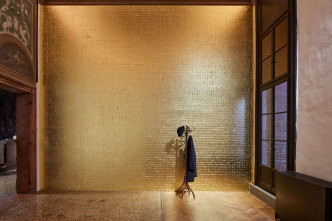 Jannis Kounellis , Untitled (Tragedia civile), 1975, Goldleaf-coated wall, coat rack, coat, hat, lamp, Installation view, Jannis Kounellis, Fondazione Prada, Venice, 2019, Photo: Agostino Osio - Alto Piano, Courtesy Fondazione Prada