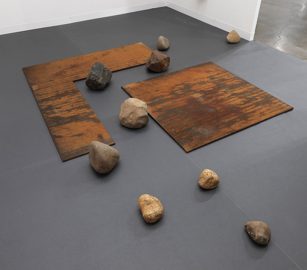 Lee Ufan, Relatum (formerly Relation), 1968/1991/2011, Steel plates and stones, L-shape steel plate: 1/2 x 59 1/4 x 67 inches, Square steel plate: 1/2 x 43 1/4 x 43 1/4 inches, 9 stones, variable: 10 x 11 x 11 inches; 3 x 5 x 5 inches, © Lee Ufan, Courtesy the artist and Blum & Poe Gallery