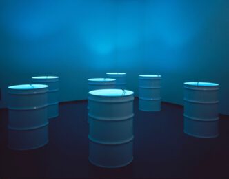 Bill Viola, The Sleepers, 1992, Seven channels of black-and-white video images on seven small monitors, each sumerged on the bottom of a 55-gallon white, metal barrel filled with water; large dark room, Room dimensions: 12 x 20 x 25 ft (3.7 x 6.1 x 7.6 m), Continuously running, Edition 2 of 2, Courtesy Bill Viola Studio & Kukje Gallery