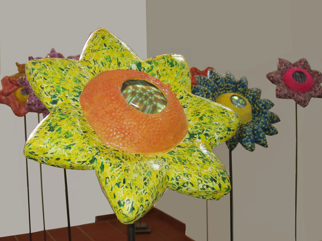 Ioanna Kazaki, Microcosmos–Macrocosmos, 17 Flowers, Polyester, digital images, papier mache, collage, stainless mirror, iron, magnifying lenses, lights. Sound: Stadium Crowd Noise, Dimentions: 150x30x30cm or 165x45x45cm each/ Installation view AcroArt Projects-Thessaloniki, 2026, © & Courtesy the artist