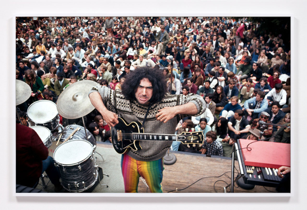 Jerry Garcia performing in Golden Gate Park, San Francisco, CA, 1967 / 2025, Archival giclée print, 32 5/8 × 50 5/8 × 2 in | 82.9 × 128.6 × 5.1 cm with frame included, Edition of 3 + 1AP, © Ron Rakow, courtesy of the artist and David Kordansky Gallery