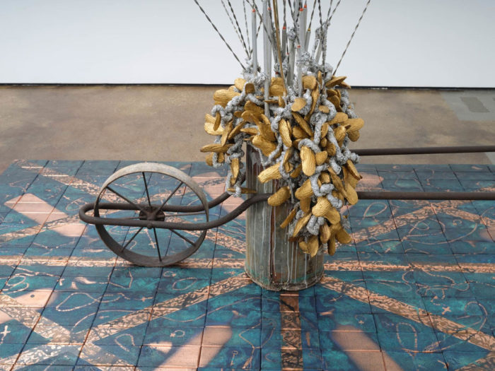 Nari Ward, Balance Fountain, 2013-2014, Wheel barrow, window balances, mango seeds, Aluminet shade cloth, broken mirror, 62.99 x 72.83 x 22.44 inches, 160 x 185 x 57 cm, © Nari Ward. Installed with: Nari Ward, Groundin' Visible, 2023, Copper, darkening patina, bricks, 2.5 x 75 x 117 inches, 6.4 x 190.5 x 297.2 cm, © Nari Ward. Photo by Daniel Kukla. Courtesy the artist and Lehmann Maupin Gallery