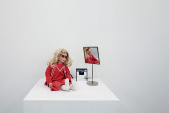 Lynn Hershman Leeson, CyberRoberta, 1996, mixed-media installation; custom-made doll, textile, glasses, webcam, surveillance camera, mirror, original programming, and telerobotic head-rotating system, approximately 45 x 45 x 20 cm. Courtesy of Hess Art Collection GmbH, Bolligen, Switzerland