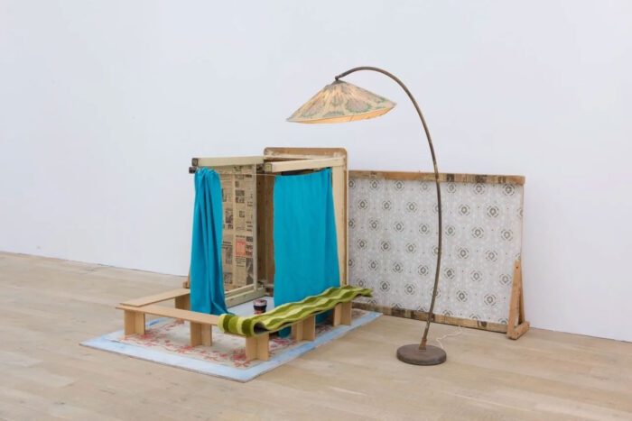 Vlassis Caniaris, Child's room, 1974 , Environment made of pasted newspapers and wallpaper, floor lamp, turned over table, curtains, carpet, 3 cups, jam jar, painted plywood boards, metal boar, 150 x 256 x 145 cm (59.1 x 100.8 x 57.1 in.), Courtesy Kalfayan Galleries and Galerie Peter Kilchmann. Photo credit: Kalfayan Galleries