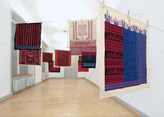 Mona Hatoum (with the women of Inaash), Twelve Windows, 2012–2013, Twelve Palestinian embroideries on fabric, wooden clothespins, and steel cable, Each 100 × 100 cm, overall installation dimensions variable, Installation view at Kunstmuseum St. Gallen, 2013, © Mona Hatoum. Courtesy of Kunstmuseum St. Gallen (photo: Stefan Rohner)